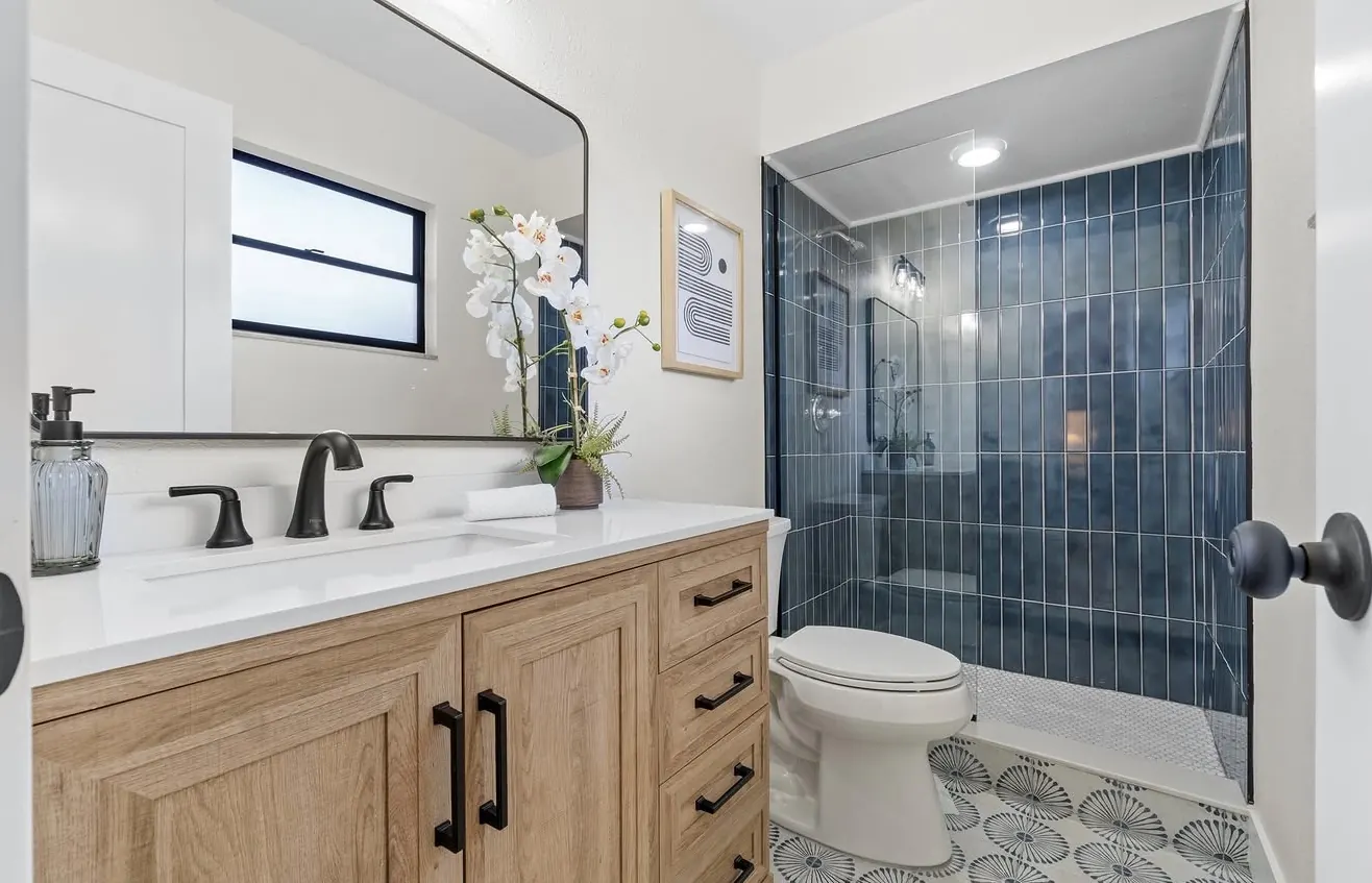 Bathroom with blue tile walk-in shower by CWL Construction